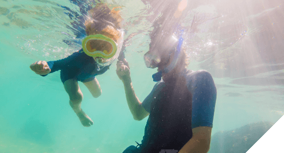 Viajes en familia. Experiencias para todos. Padre e hijo hacen snorkel en aguas turquesas