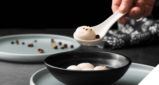 Experiencias premium. Momentos wow. Deliciosa comida presentada en un bol negro con cuchara de cerámica blanca