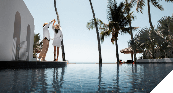 Experiencias premium. Momentos wow. Una pareja baila en el borde de una piscina cerca de una casa blanca y palmeras