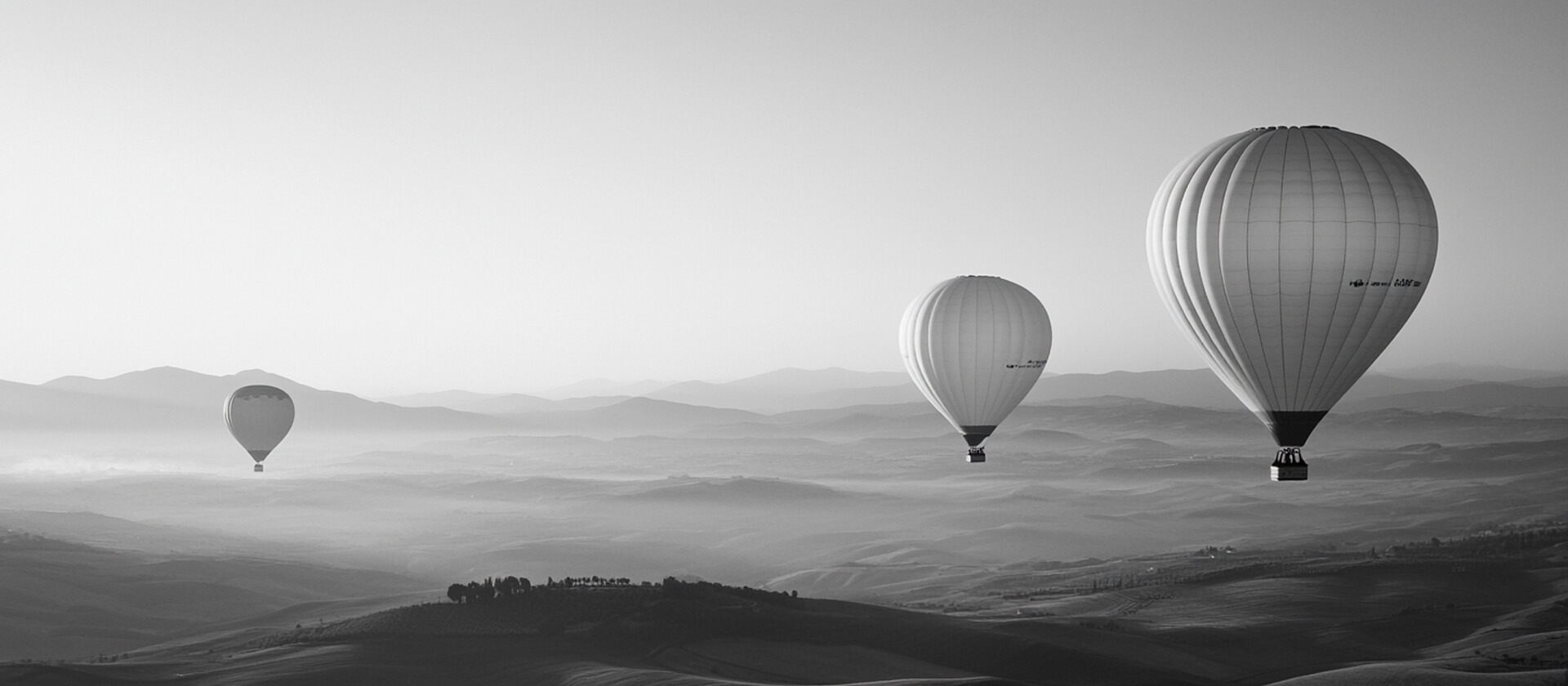 Viajes a medida. Experiencias inolvidables. Tres globos aerostáticos viajan por el cielo en un paisaje natural
