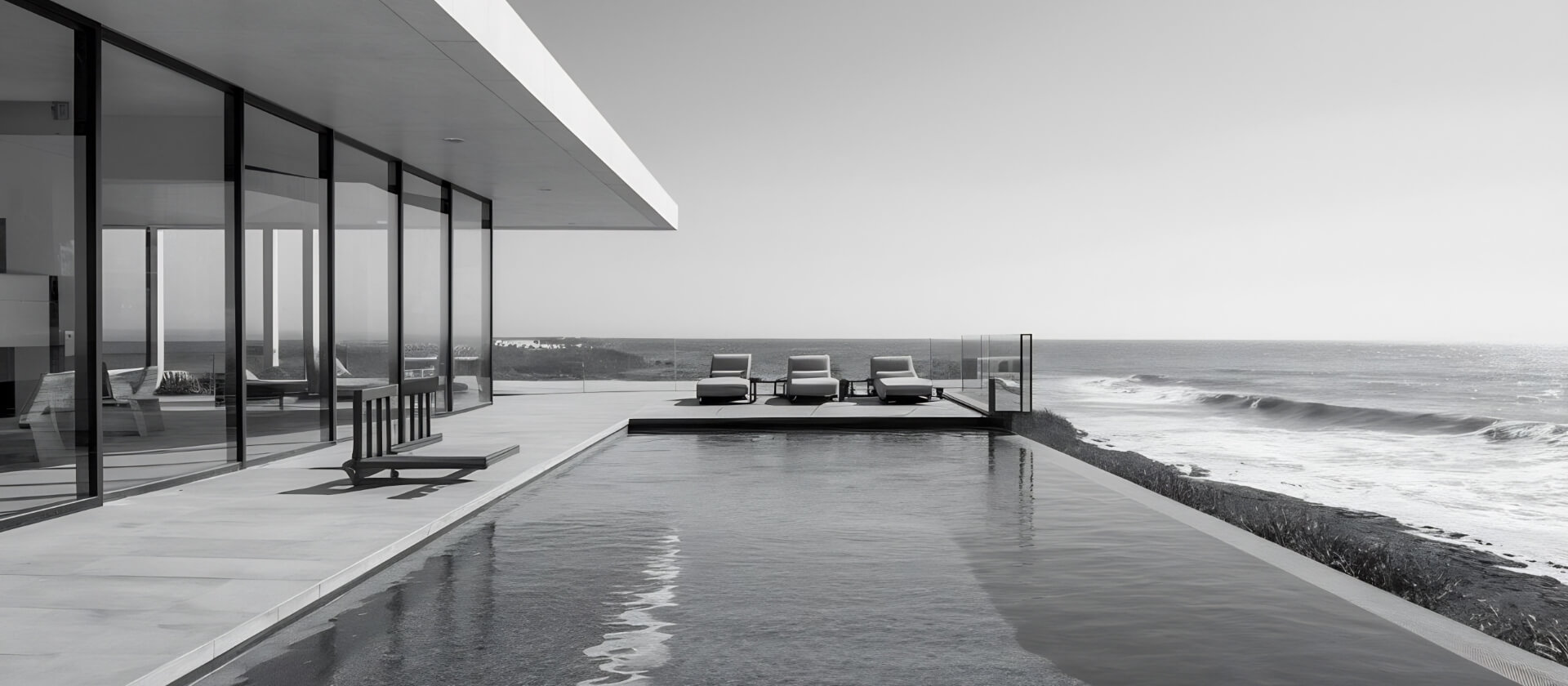 Experiencias premium. Tres hamacas y una piscina con el mar en el horizonte al lado de una casa acristalada