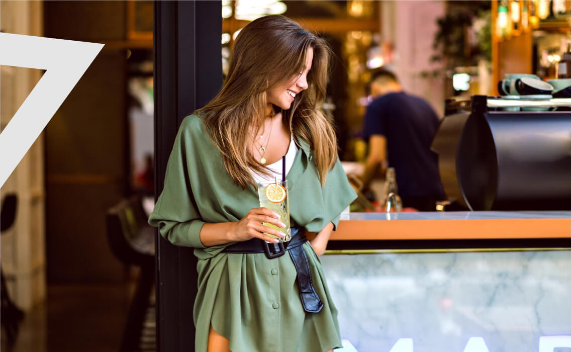 Experiencias Premium. Mujer sonriente con un vaso en la mano en un establecimiento de hostelería