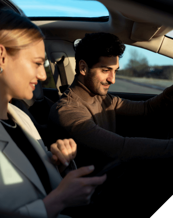 Experiencias premium. Muévete por tierra. Una pareja sonriente viaja en un coche con el techo solar abierto