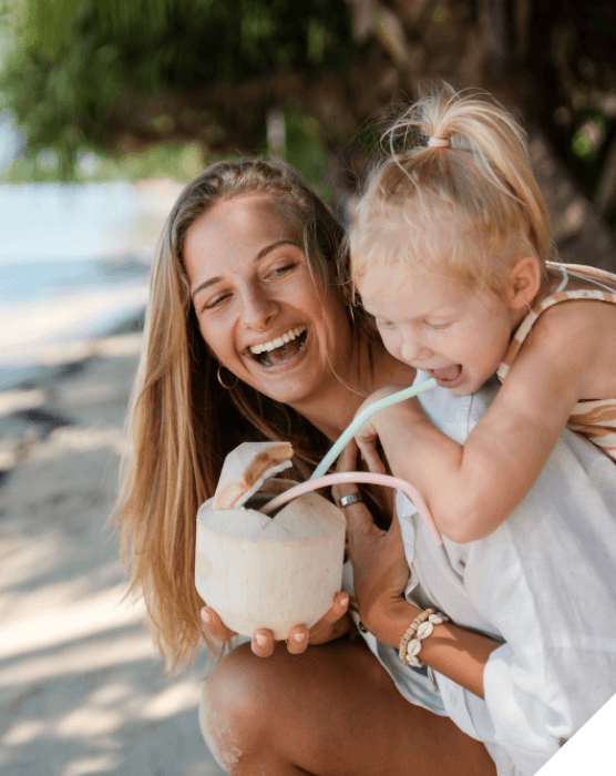 Viajes en familia. Viajes originales. Una madre y su hija comparte un refresco en la playa en Tailandia