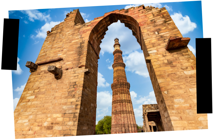Viajes a medida. Viajes que inspiran. Un imponente minar se divisa a través del gran arco de la puerta de un templo en ruinas