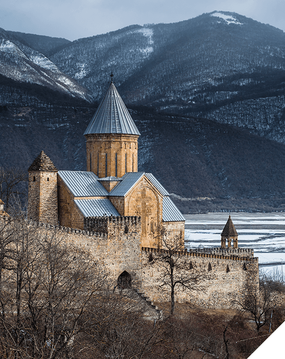 Viajes a medida. Destinos singulares. Iglesia frente a un lago en un paisaje de montañas con las cumbres nevadas