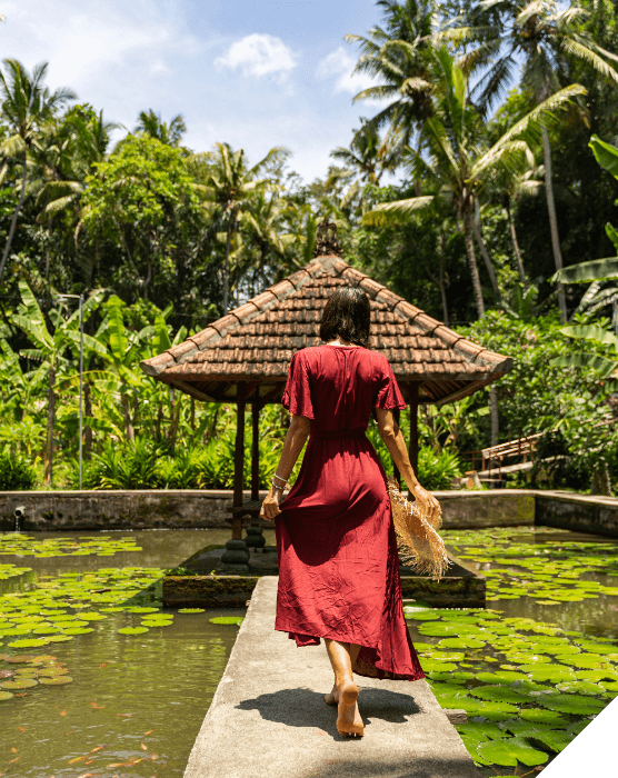 Viajes de novios. Verano. Una mujer vestida de rojo camina descalza sobre una plataforma encima de un lago en Sri Lanka