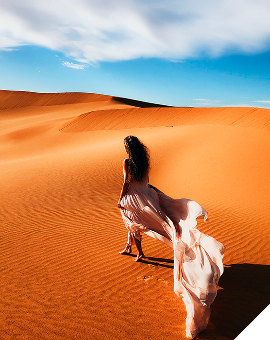 Viajes de novios. Otoño. Una mujer con vestido claro pasea por la arena del desierto de dunas