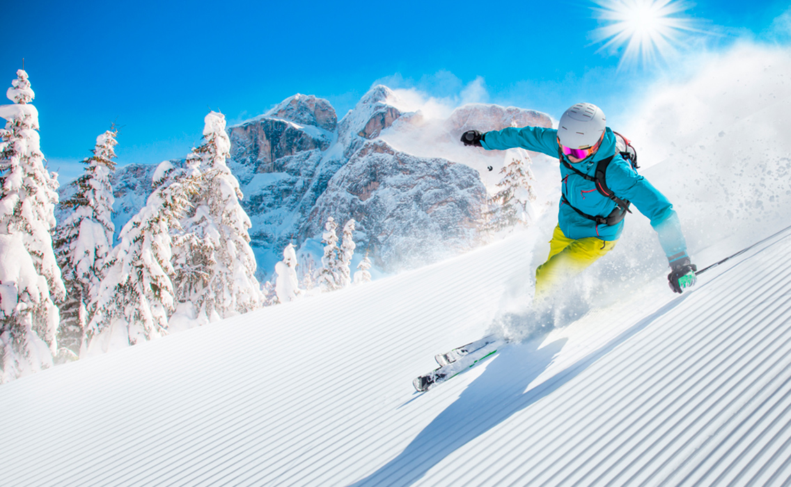Esquiador disfrutando de una bajada perfecta en los Dolomitas, entre nieve impecable y paisajes únicos de los Alpes italianos en un viaje de lujo a medida.