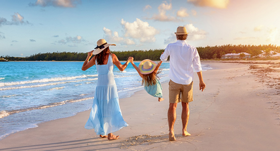 Familia paseando de la mano por una playa paradisíaca durante un viaje de lujo a medida, diseñado para disfrutar con tranquilidad y sin imprevistos