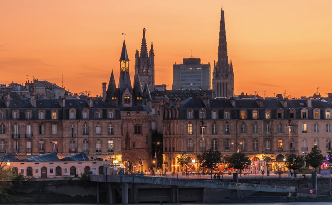 Ciudad de Burdeos de noche, luces reflejadas en el Garona, destino ideal para viajes de lujo a medida y experiencias exclusivas