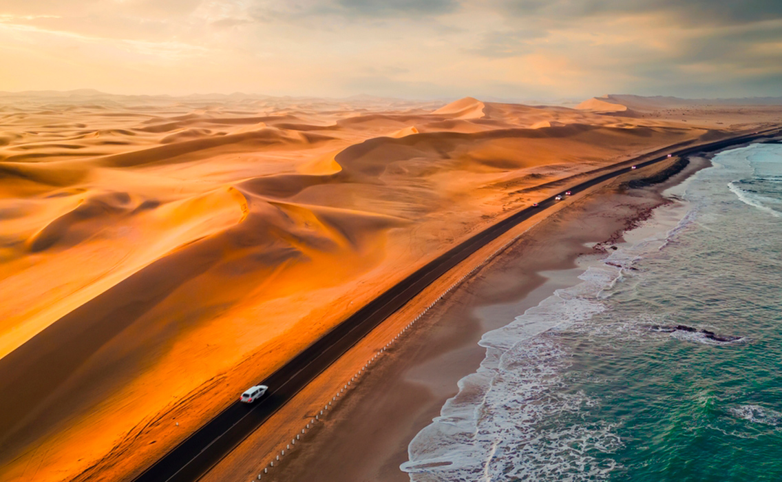 Vista aérea de carretera en la Costa de los Esqueletos en Namibia, entre desierto y océano Atlántico al atardecer durante un viaje de lujo a Namibia a medida.