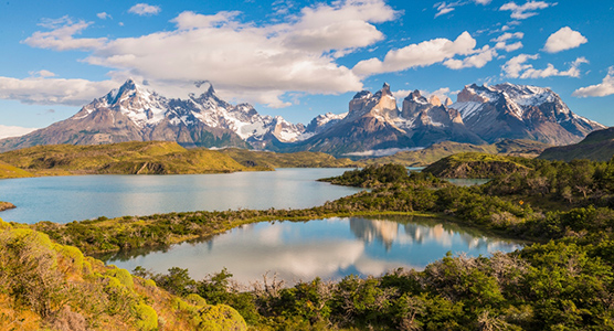 Necesito que actúes como un experto en redes y me digas dos frases que ilustren una foto donde aparece una vista de Torres del Paine con lago y al fondo montañas ligeramente nevadas, en Chile. El artículo se titula: Patagonia chilena en abril: paisajes inmensos, menos viajeros y una aventura más exclusiva. Elabora una frase es para el texto alternativo de un post y otro para el título de la foto. Tiene que ser frases óptimas para SEO. Tienen que tener un enfoque de viajes de lujo y a medida. Dame dos opciones de frases ya que la misma foto va en portada y en interior.