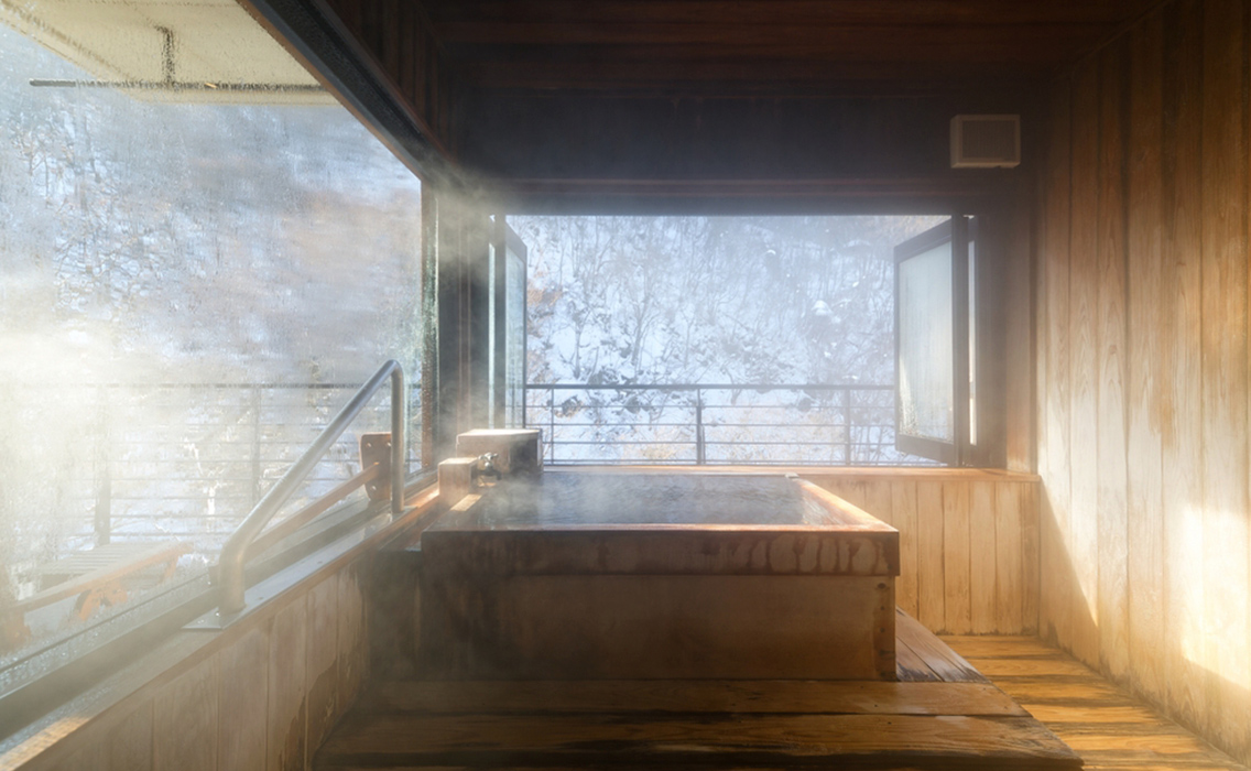 Baño termal japonés entre montañas nevadas en Hokkaido, una experiencia de onsen rodeada de naturaleza y silencio invernal.