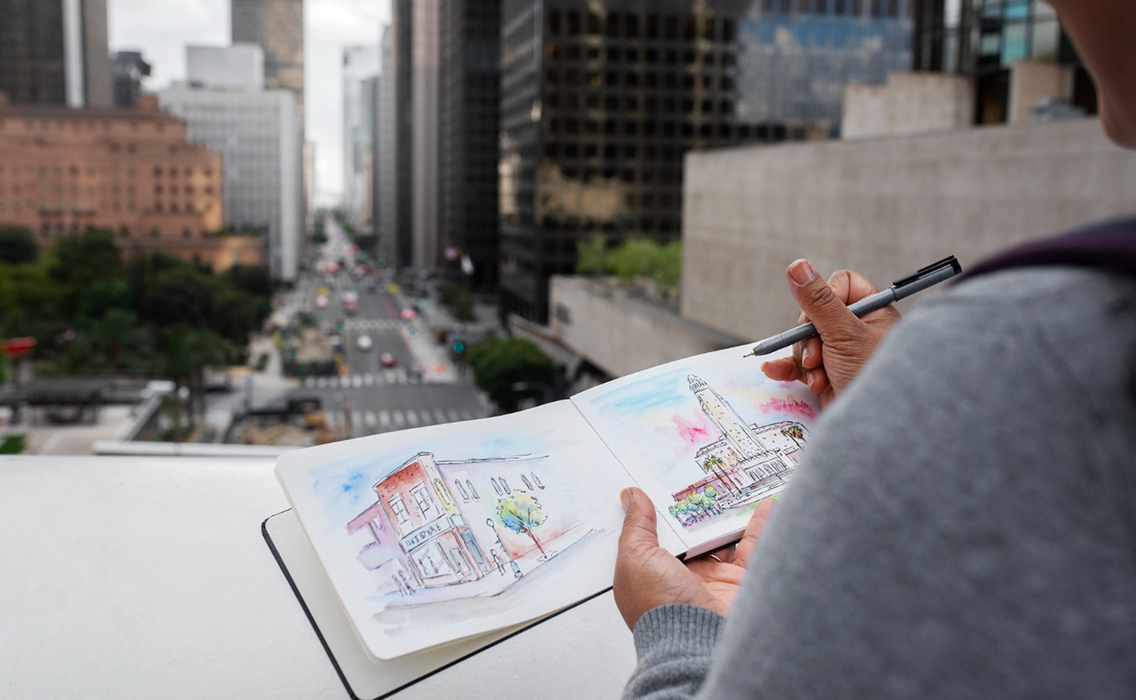 Persona sentada frente a un monumento realizando un dibujo en su cuaderno durante un viaje de lujo diseñado para disfrutar cada momento sin prisas.