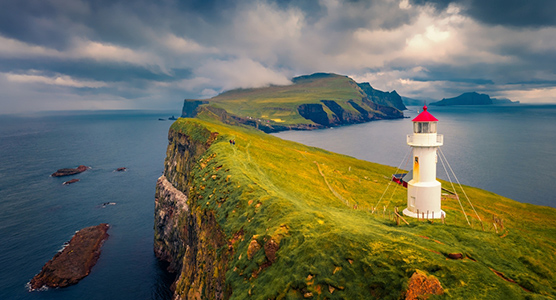 Puesta de sol de verano en la isla de Mykines y su faro, durante un viaje de lujo a las Islas Feroe.