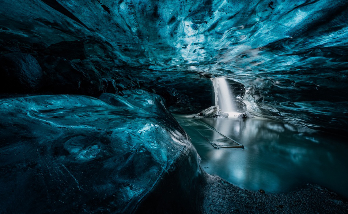 Interior de una cueva de hielo azul en Islandia con formaciones glaciares iluminadas por luz natural durante un viaje de lujo a medida.