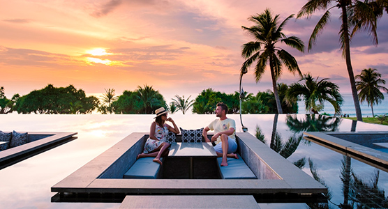 Pareja disfrutando de una puesta de sol desde una piscina infinita en Tailandia durante un viaje de lujo a medida.